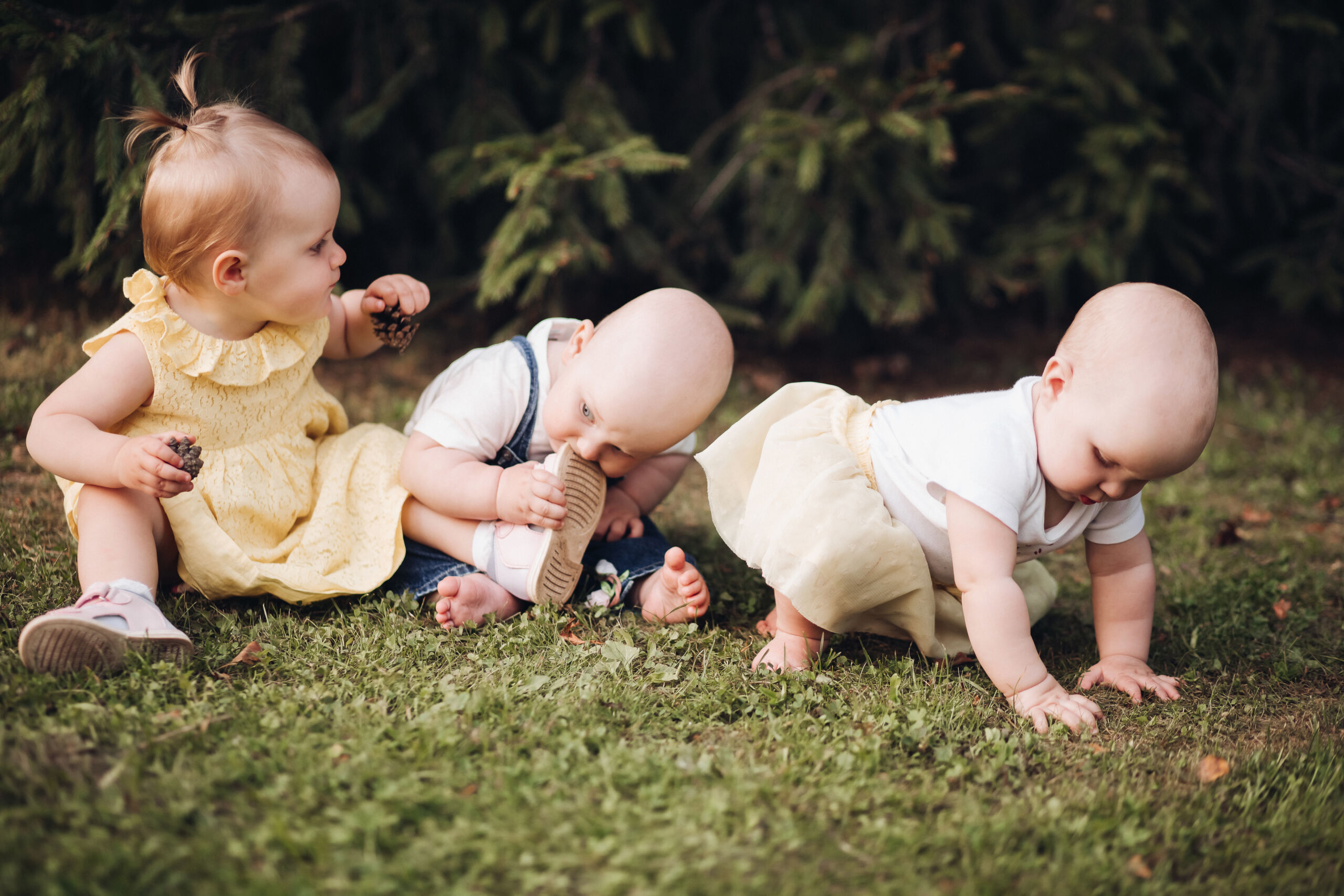 Three little children crawl on a green grass and have fun togehter