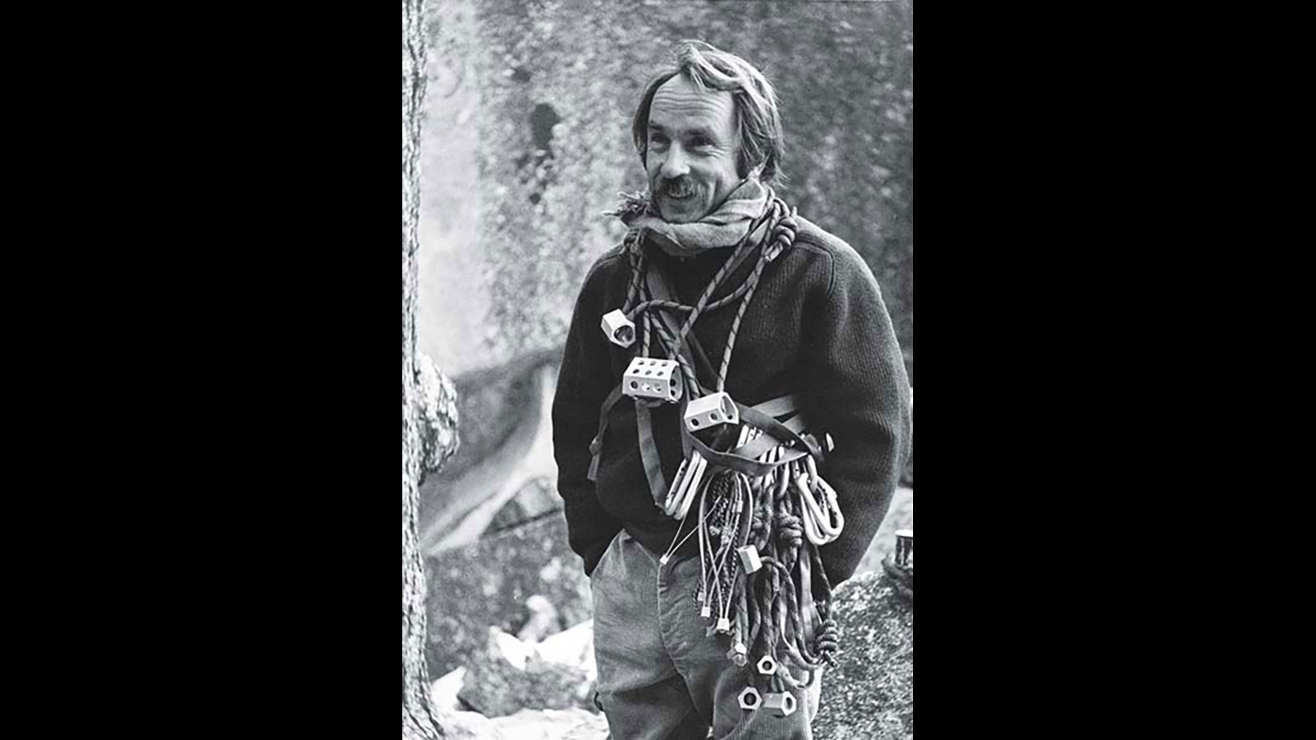 Yvon Chouinard up in the mountains with climbing gear around his neck.