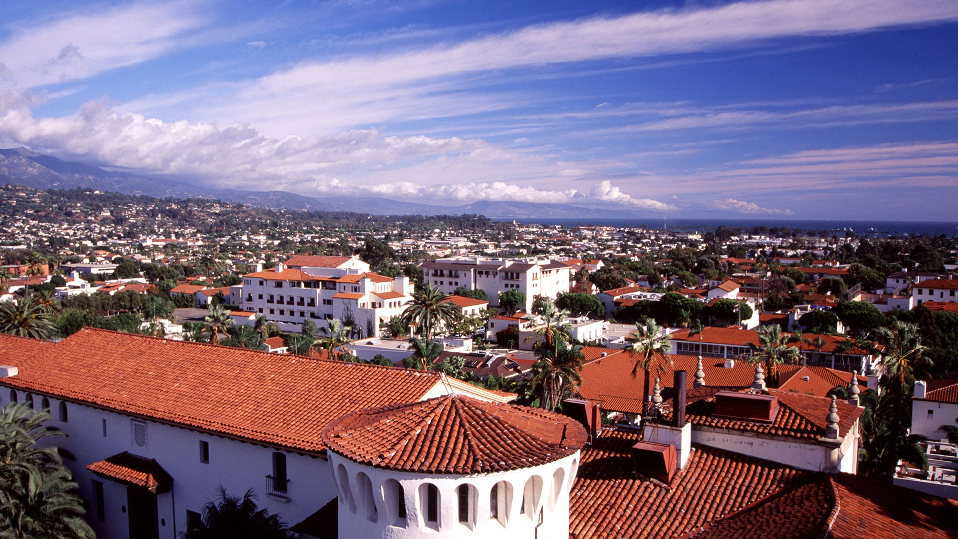 View of red tile rooftops, mountains and blue sky in Santa Barbara